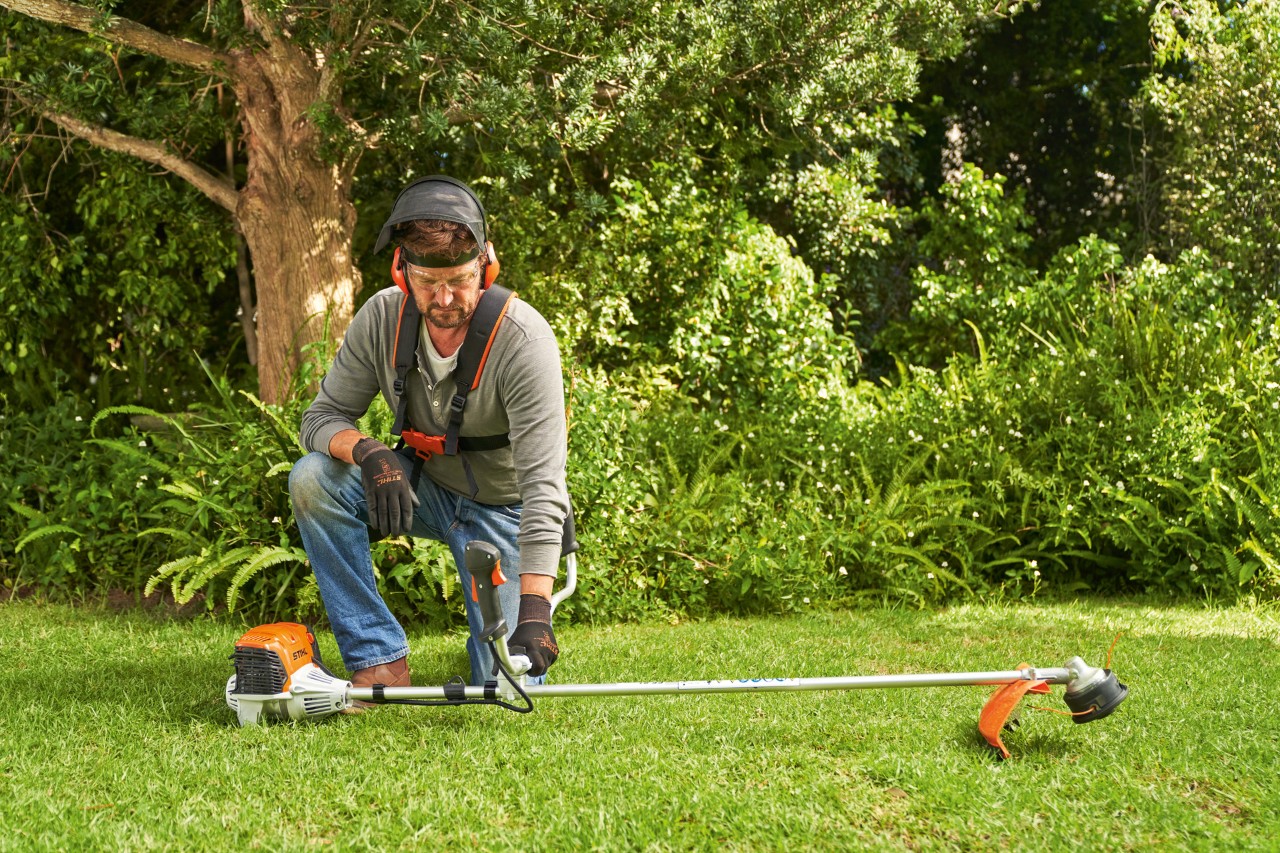 エンジン刈払機STIHL FS 91を地面に置いて、同機を始動しようとしている男性