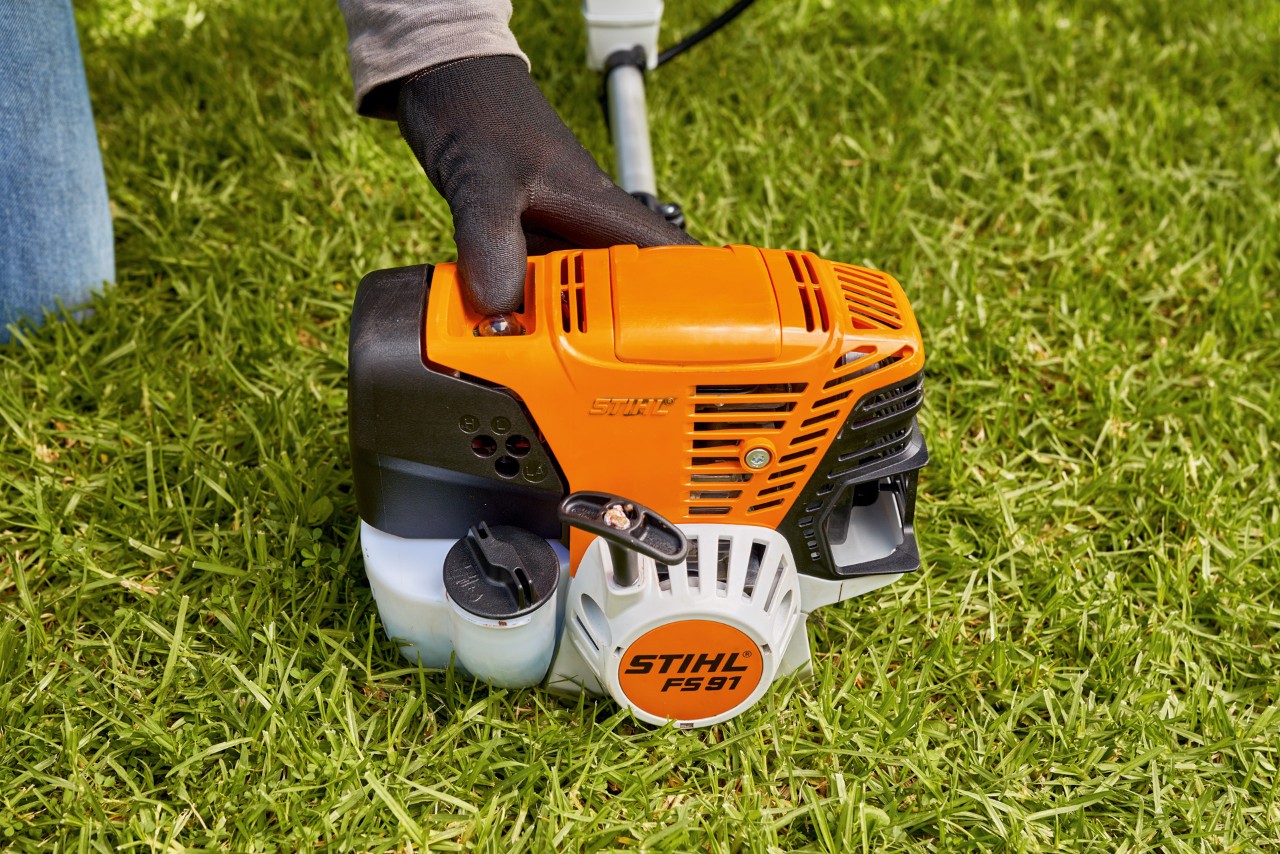 エンジン刈払機STIHL FS 91の燃料ポンプを押して、同機を始動しようとしている男性