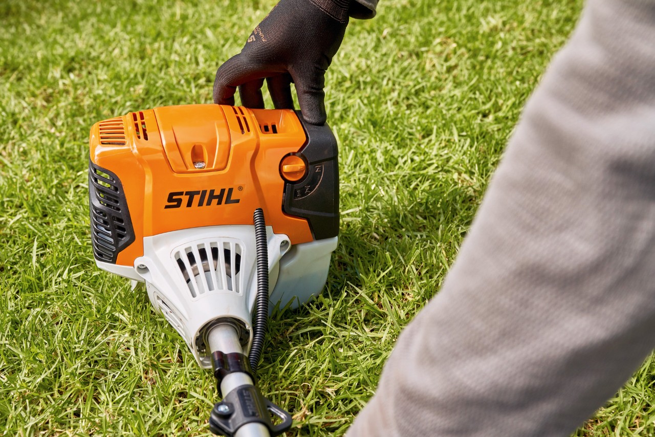 エンジン刈払機STIHL FS 91を地面にしっかりと押し付けている男性