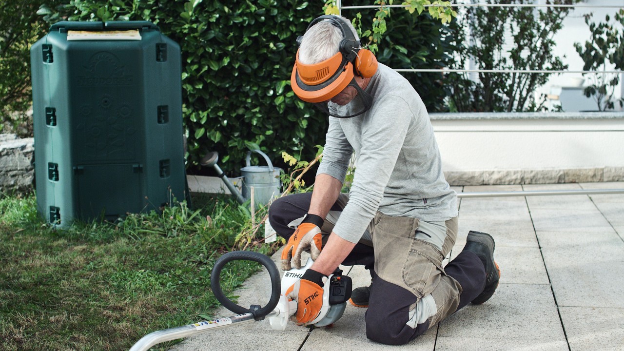 作業用防護服を着用して、エンジン刈払機STIHL FS 38を地面に押し付けている人物