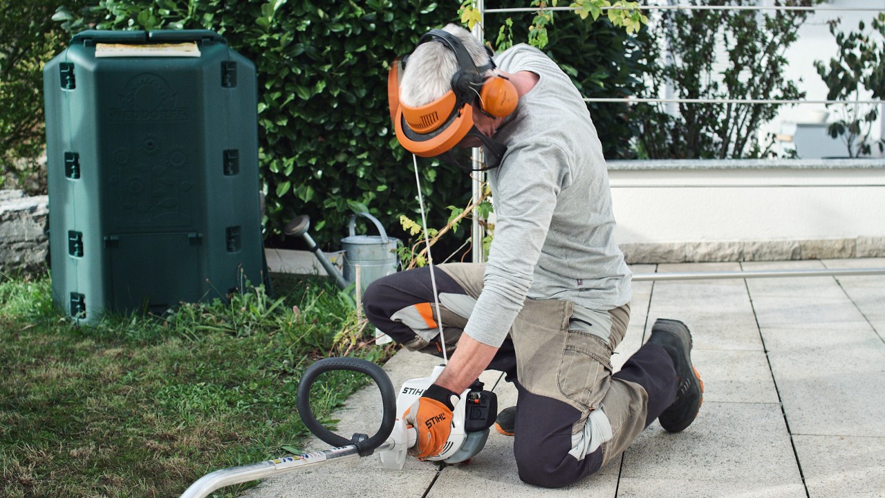 作業用防護服を着用して、エンジン刈払機STIHL FS 38のスターターロープをもう一度引っ張っている人物