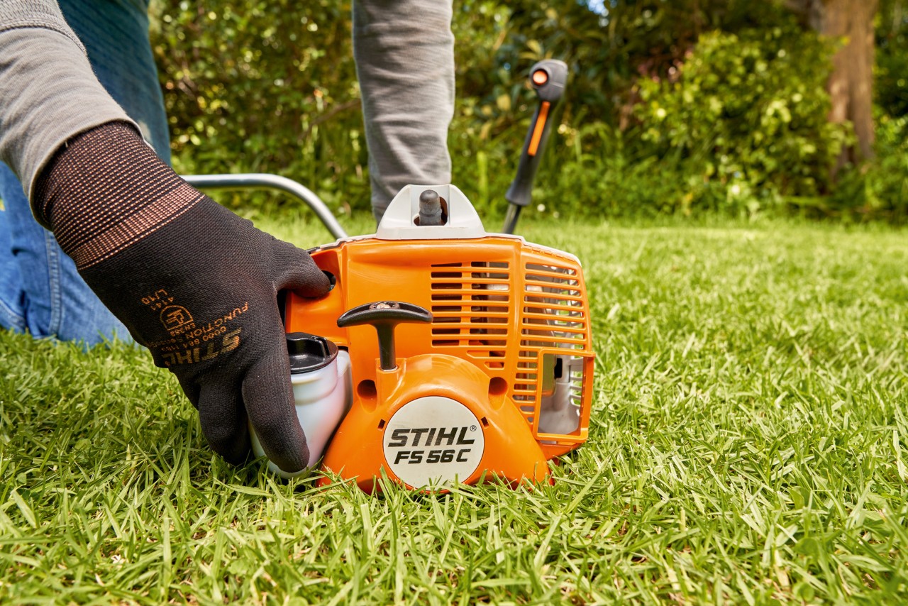 エンジン刈払機STIHL FS 56の燃料ポンプを押して、同機を始動しようとしている男性