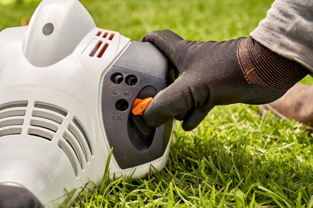 エンジン刈払機STIHL FS 56のレバーを調整して、同機を始動しようとしている男性