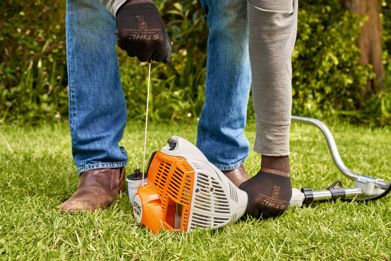 エンジン刈払機STIHL FS 56のスターターロープを引っ張っている男性 
