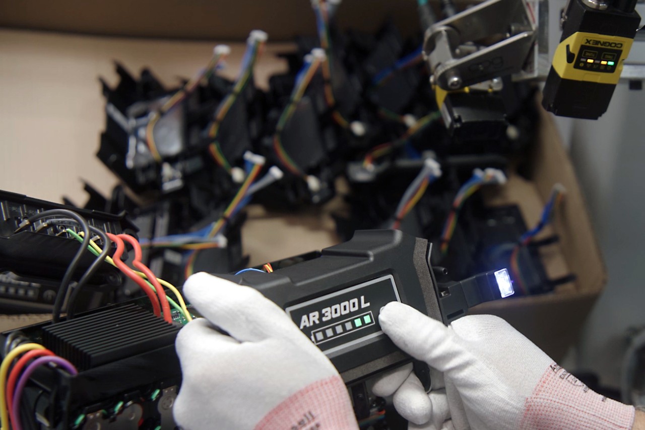 STIHLの背負式バッテリーAR 3000 Lの充電状態の緑色の表示を見る手袋をはめた人物