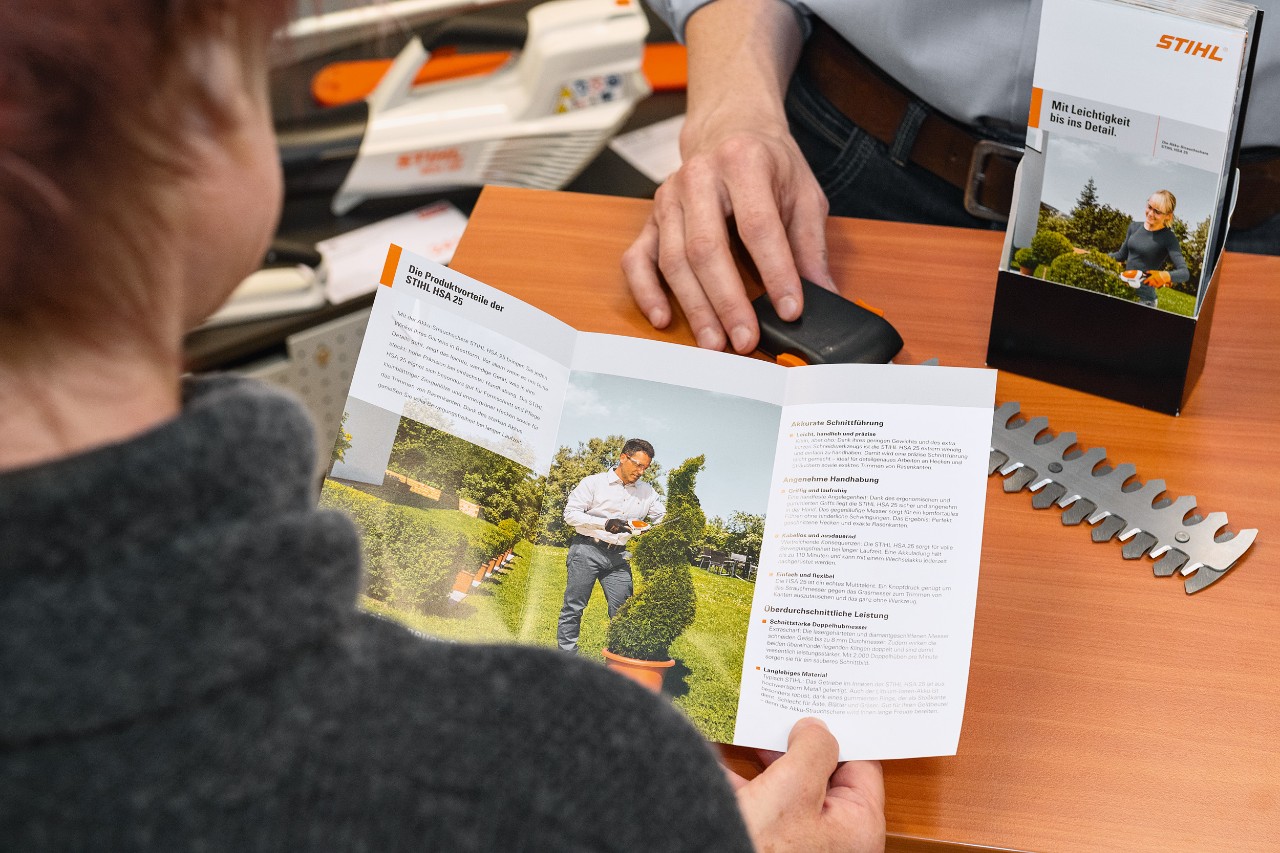 パンフレットでSTIHL HSA 25の製品メリットを見ている人物