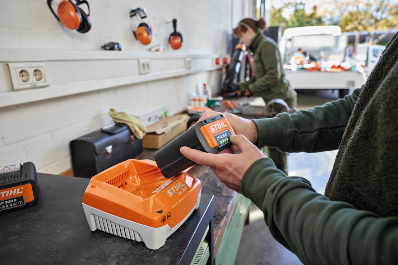 バッテリーSTIHL AP 300 Sを急速充電器STIHL AL 301に差し込む人物