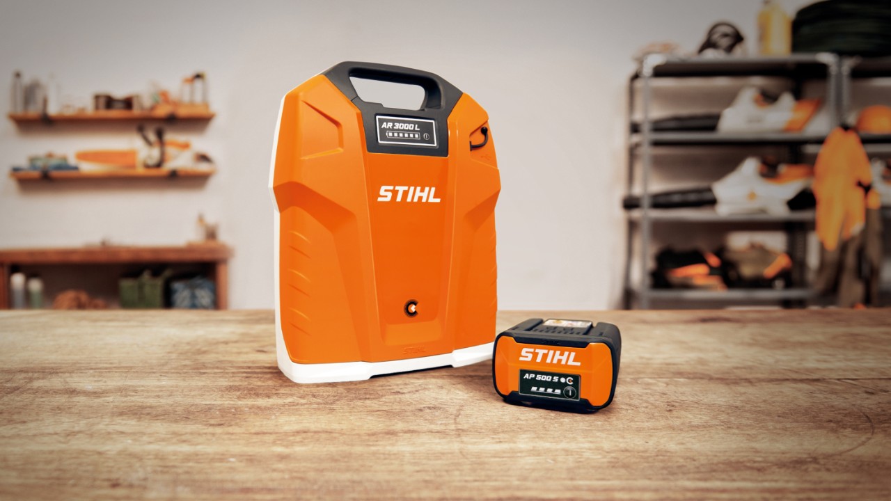 ワークショップの木製テーブルに置かれたSTIHL背負式バッテリーAR 3000 LとSTIHLバッテリーAP 500 S  